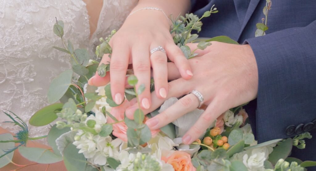 wedding couple hands on bouquet showcasing wedding rings