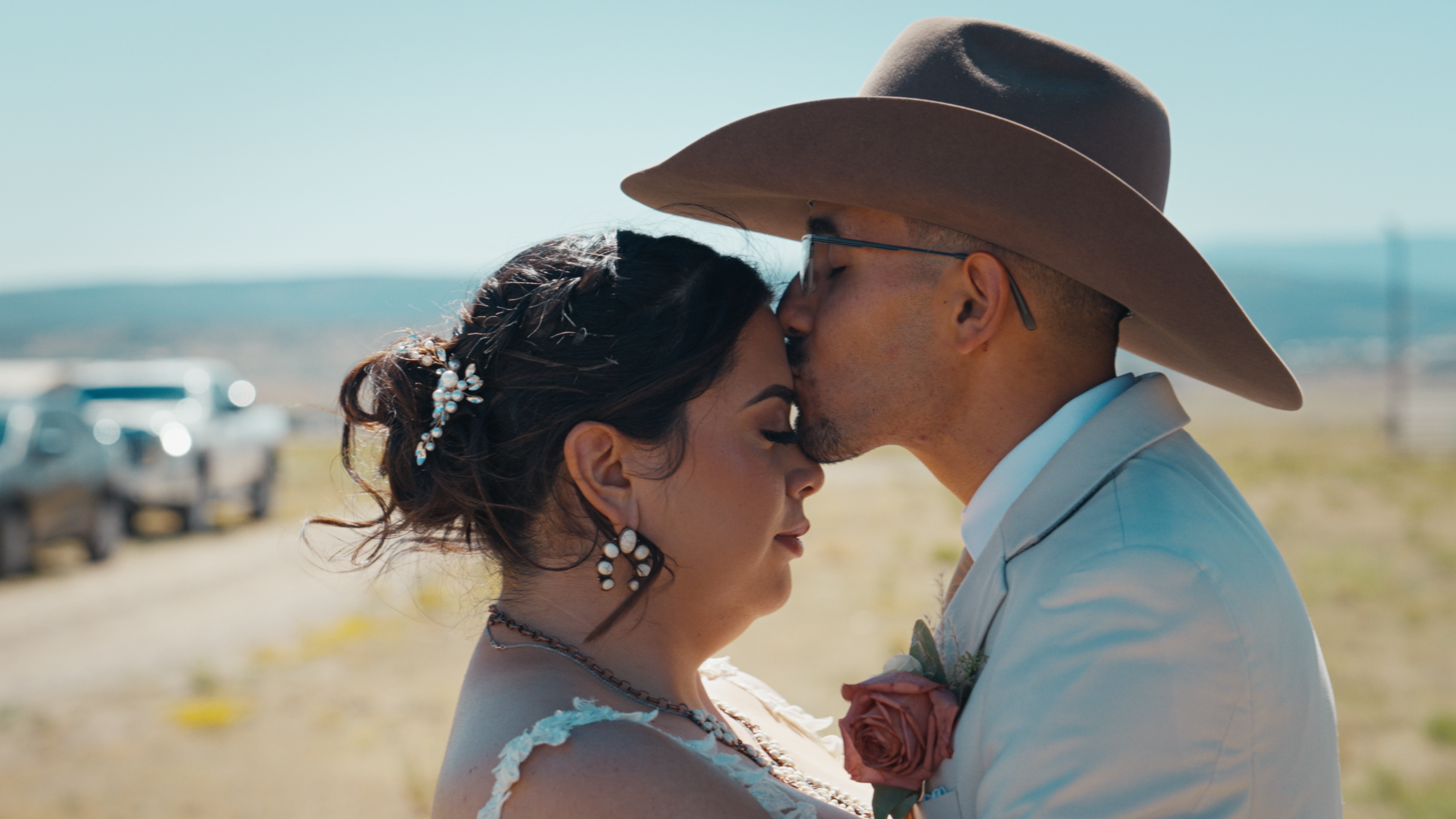 Groom giving the bride a kiss on the forehead during their outdoor wedding