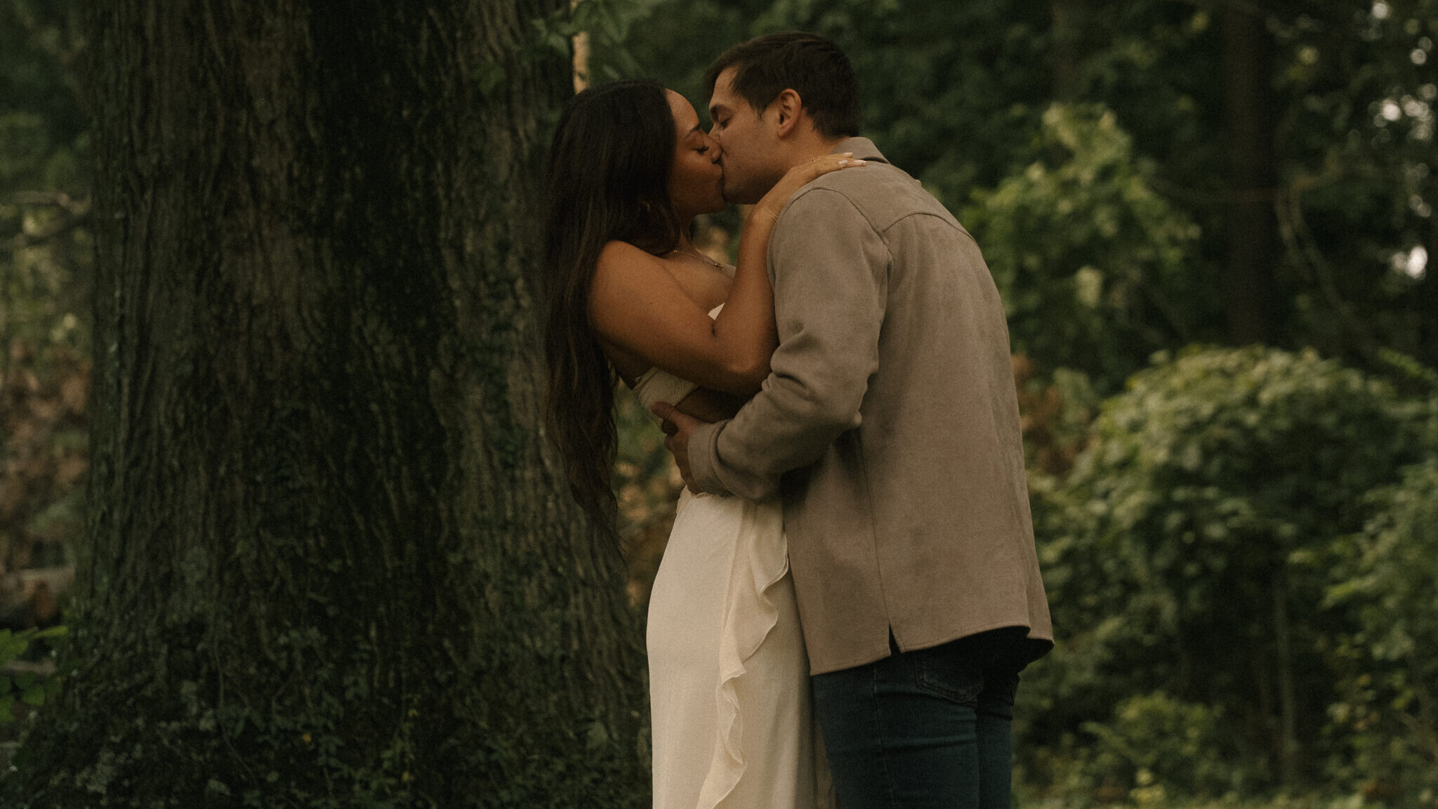 Couple kissing beneath the trees.