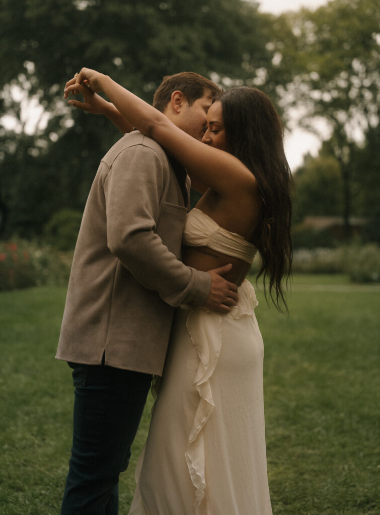 Couple embracing on a grassy lawn, with the woman’s arms around her partner’s shoulders.