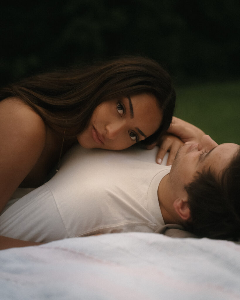 A woman resting her head on her partner as they lie together.