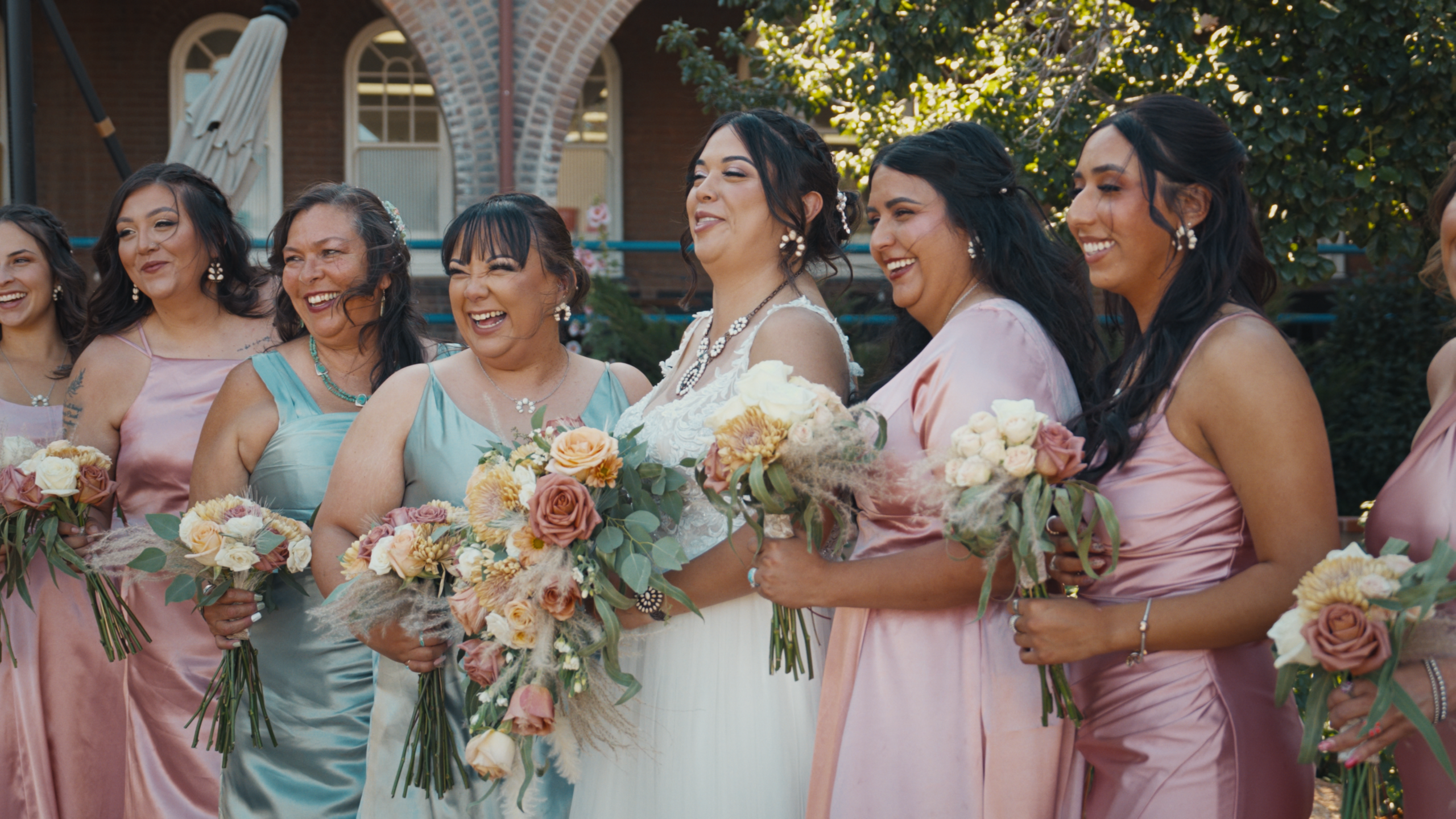 Bride and bridesmaids smiling together with colorful wedding bouquets