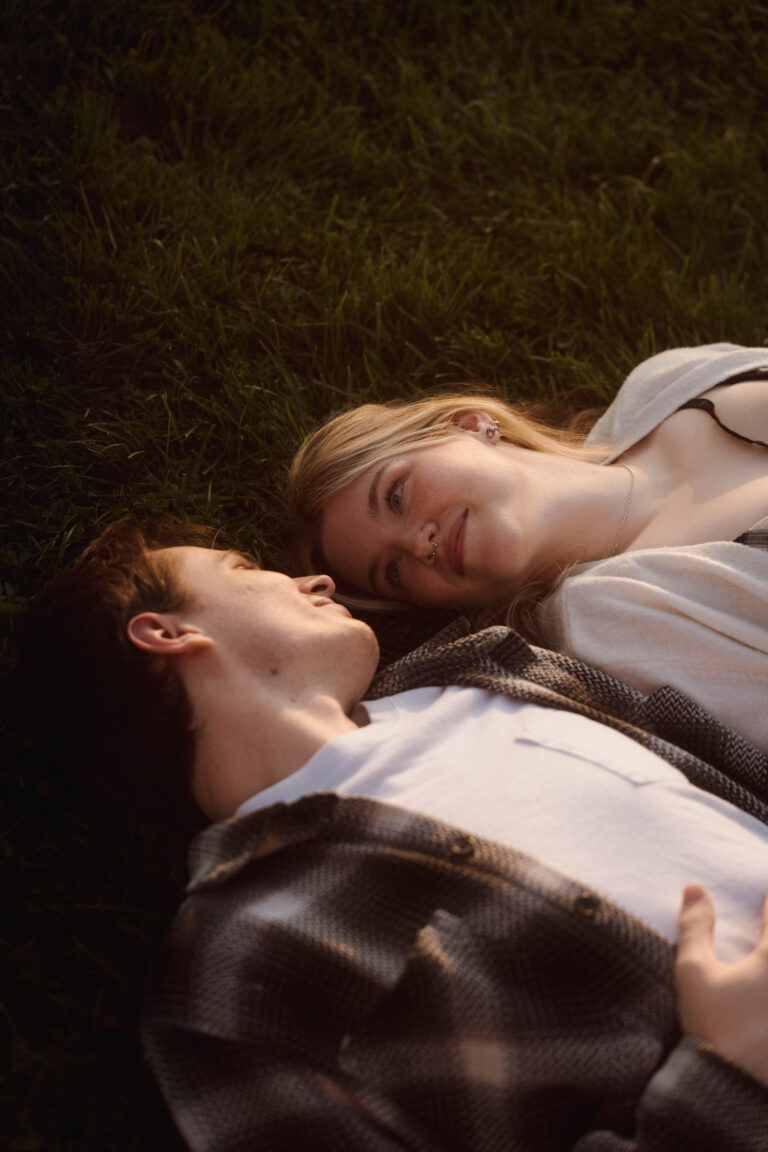 couple laying in the grass smiling at each other