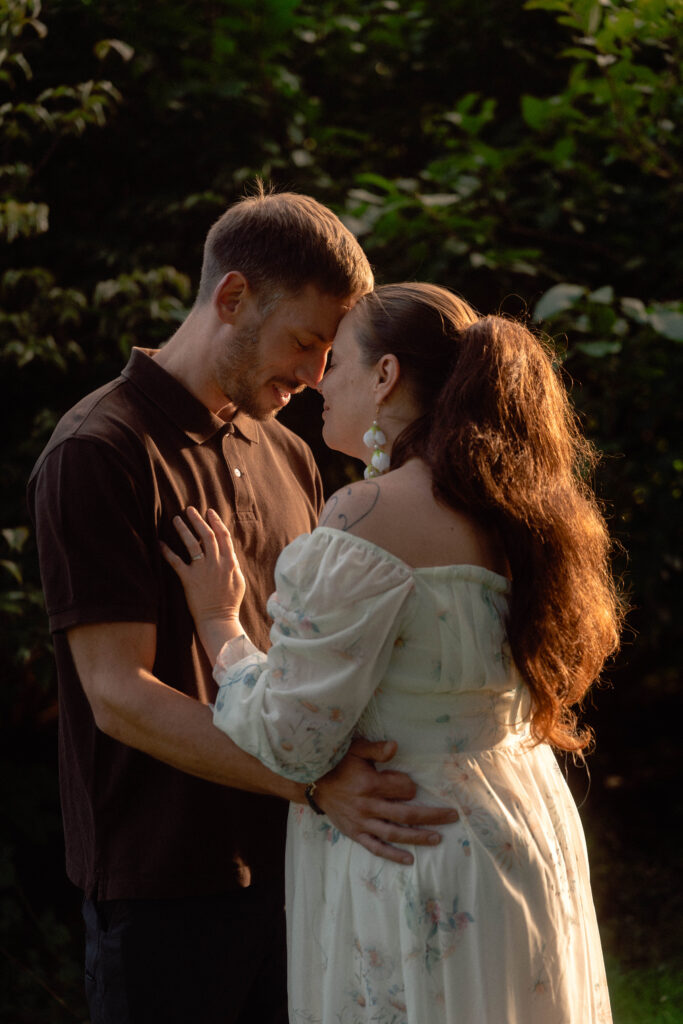 Couple touching foreheads in an embrace, with evening sunlight catching the woman’s hair.