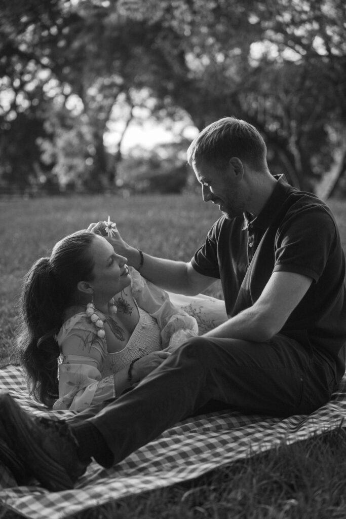 Black-and-white portrait of a couple relaxing together on a picnic blanket.