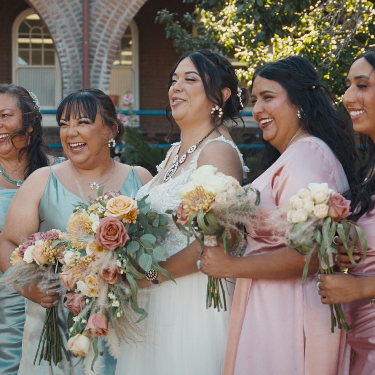 Bride and bridesmaids smiling together with colorful wedding bouquets
